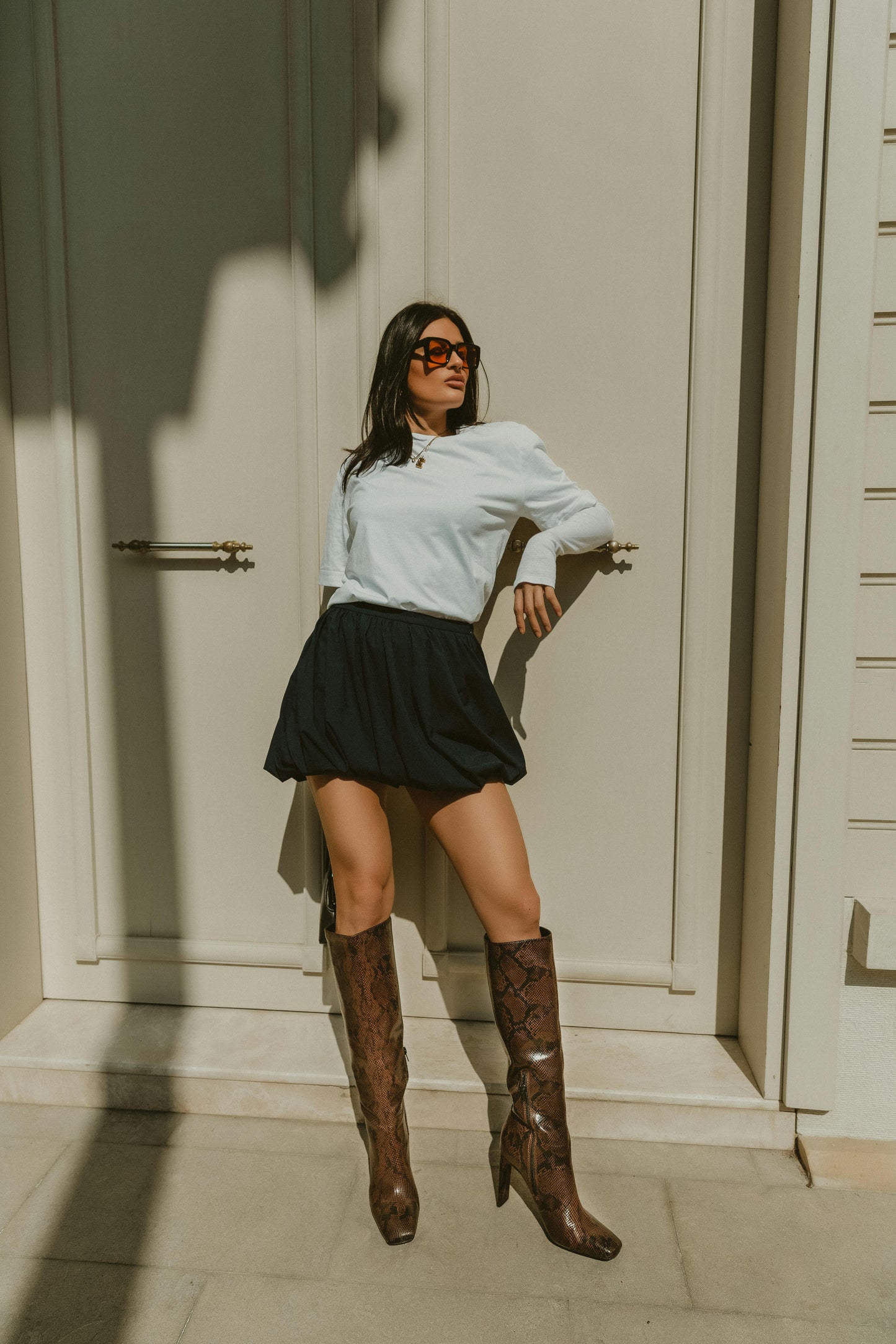 Woman leaning casually on door handle in brown leather boots and black skirt. Victoria Ellison is a Fashion Stylist specialising in Bridal Styling, Pregnancy Styling, Motherhood Styling, Personal Styling.