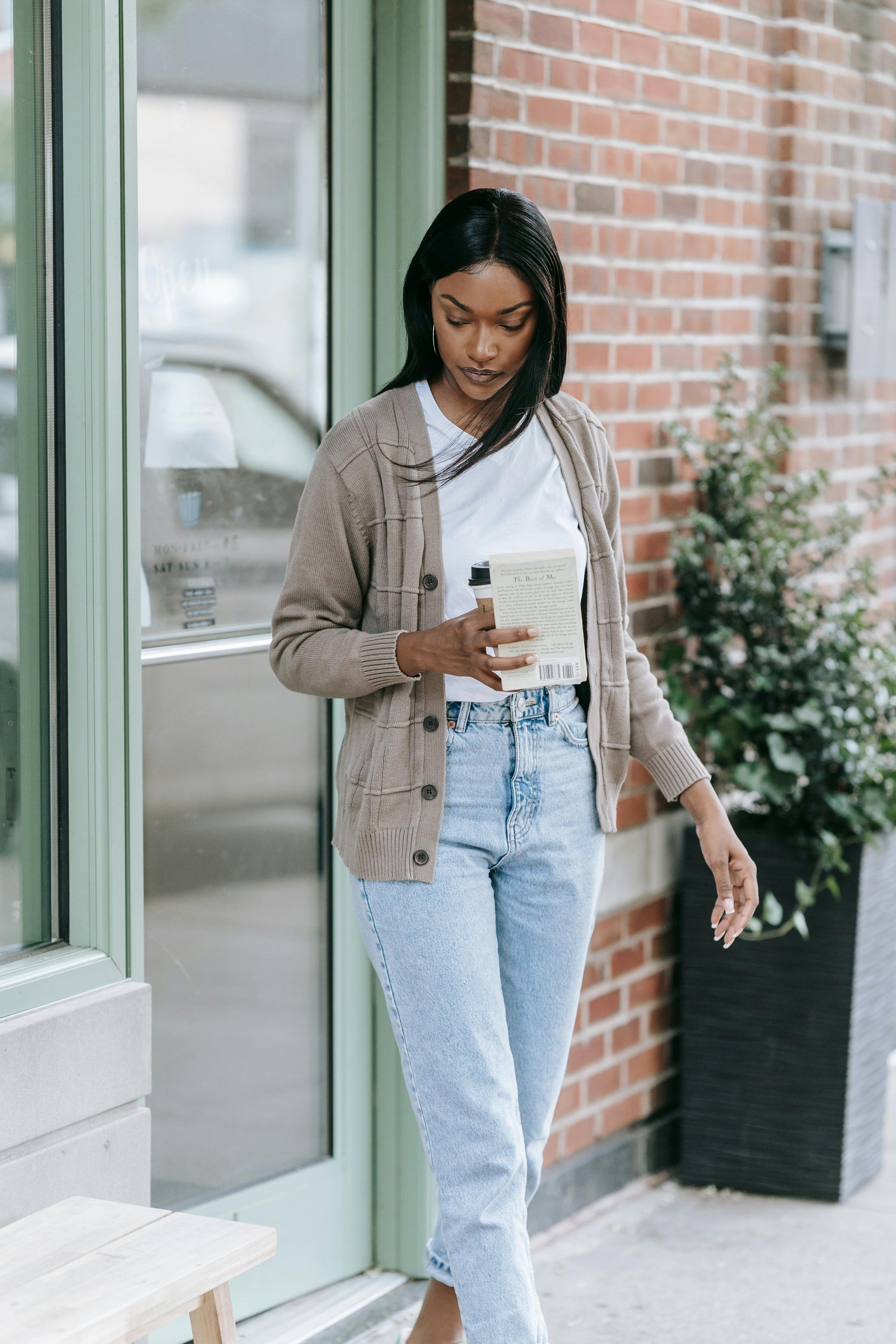 Woman standing outside a building holding a coffee cup.