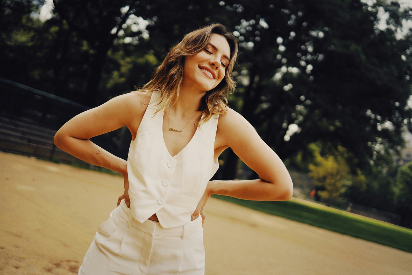 Woman in a white dress standing outdoors with trees in the background
