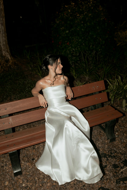 Woman in a white dress sitting on a wooden bench at night. Victoria Ellison is a Fashion Stylist specialising in Bridal Styling, Pregnancy Styling, Motherhood Styling, Personal Styling.