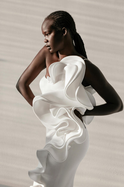 Woman wearing a white, ruffled dress against a neutral background. Victoria Ellison is a Fashion Stylist specialising in Bridal Styling, Pregnancy Styling, Motherhood Styling, Personal Styling.