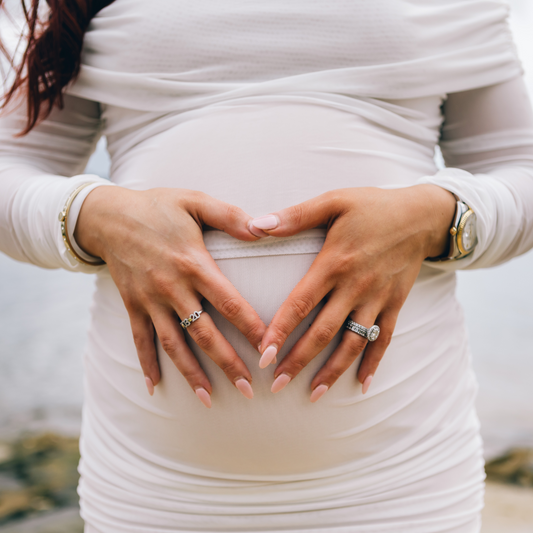 Pregnant woman with hands forming a heart shape on her belly. Victoria Ellison is a Fashion Stylist specialising in Bridal Styling, Pregnancy Styling, Motherhood Styling, Personal Styling.