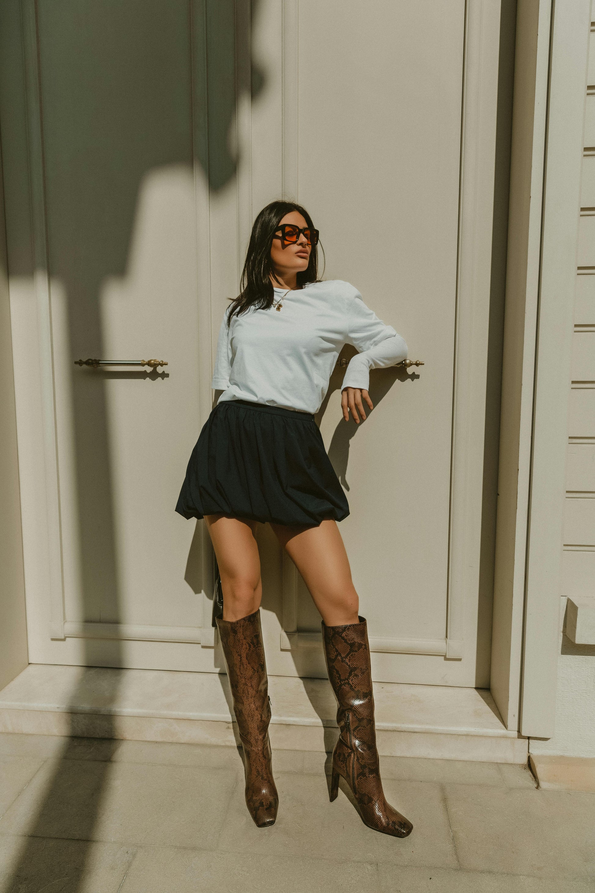 Woman leaning casually on door handle in brown leather boots and black skirt. Victoria Ellison is a Fashion Stylist specialising in Bridal Styling, Pregnancy Styling, Motherhood Styling, Personal Styling.