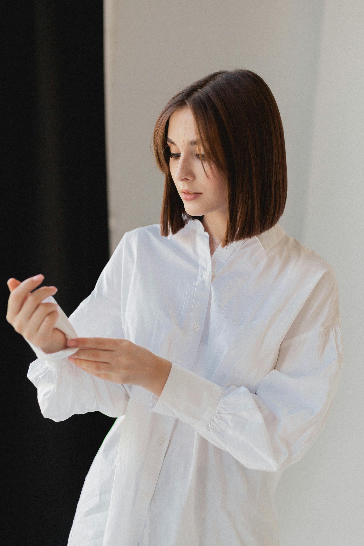 Woman in a white shirt holding a small object against a neutral background. Victoria Ellison is a Fashion Stylist specialising in Bridal Styling, Pregnancy Styling, Motherhood Styling, Personal Styling.