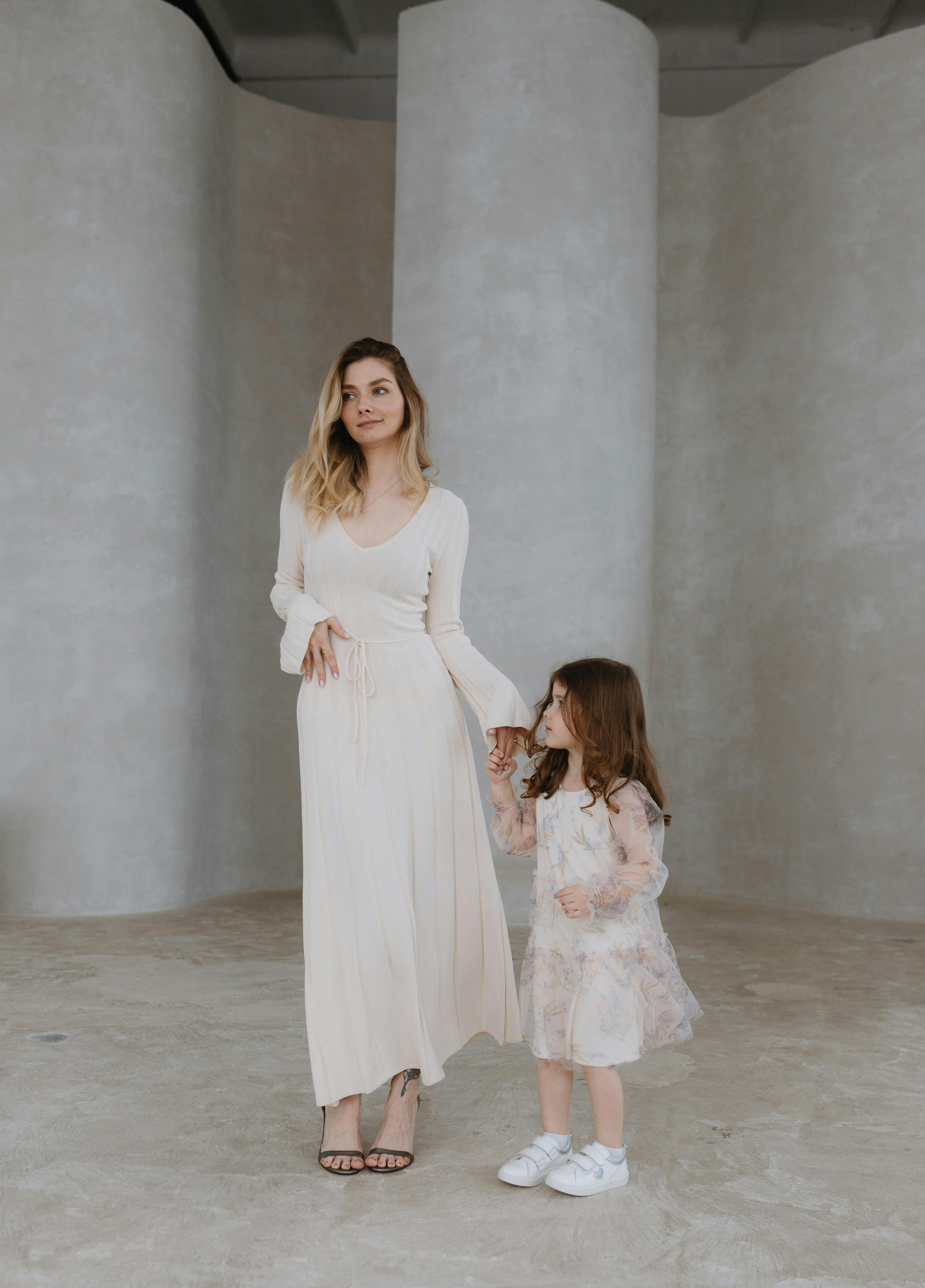 Woman and young girl holding hands in a minimalist indoor setting. Victoria Ellison is a Fashion Stylist specialising in Bridal Styling, Pregnancy Styling, Motherhood Styling, Personal Styling.