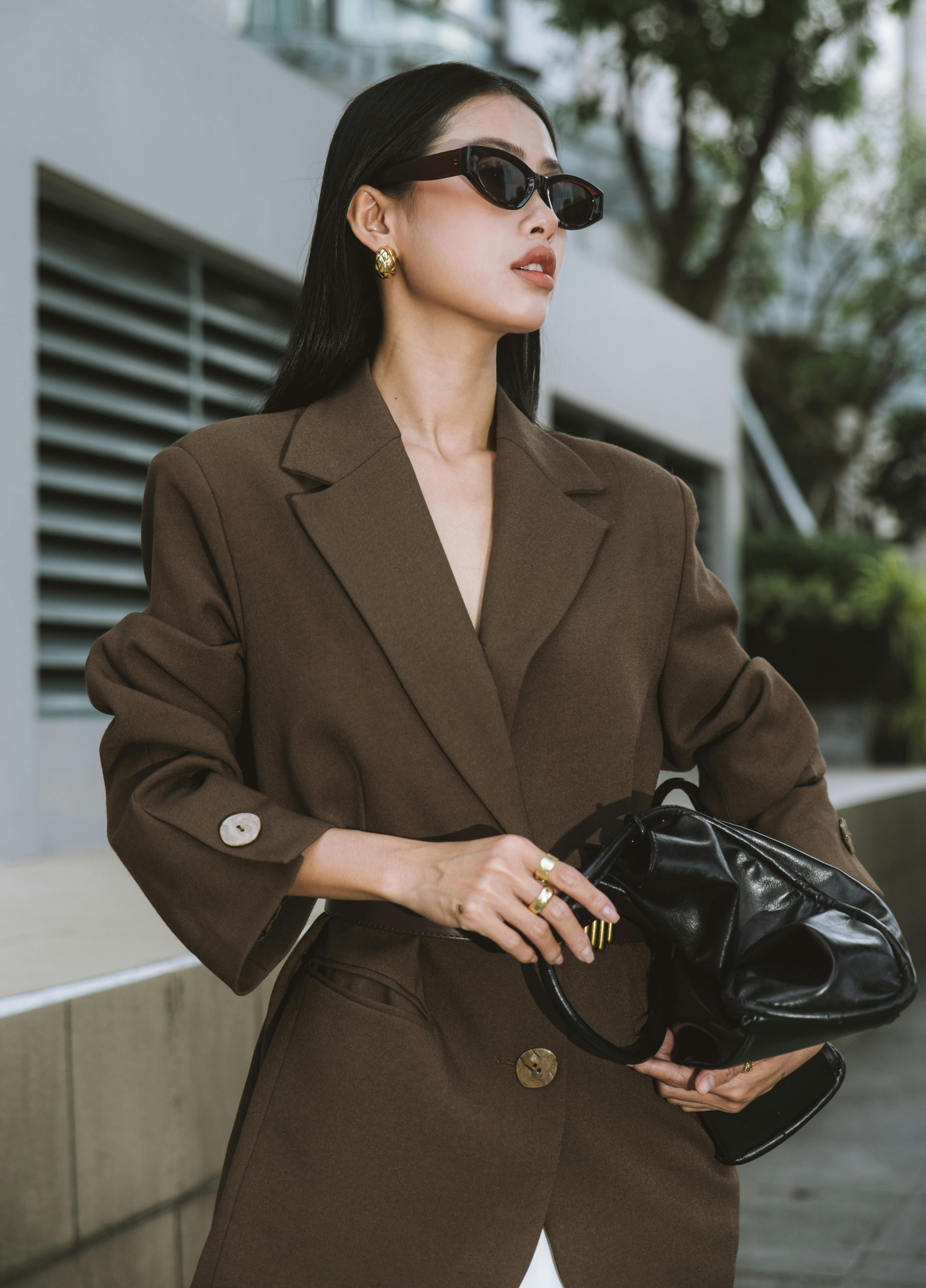 Woman in a brown suit holding a black handbag outdoors. Victoria Ellison is a Fashion Stylist specialising in Bridal Styling, Pregnancy Styling, Motherhood Styling, Personal Styling.
